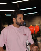Padel Beast Arabic English pink tee worn off court, front