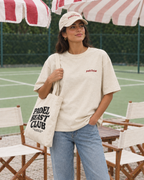 Padel stole all my money cream tee on a woman, front, with tote bag